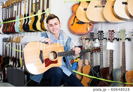 Teenager choosing acoustic guitars 60648028