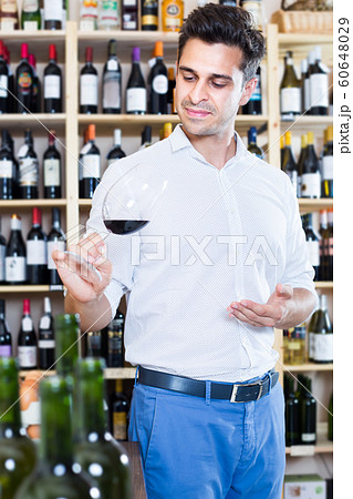 Glad man holding glass of red wine in winery section 60648029