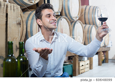 Seller holding glass of red wine in store with woods Seller holding glass of red wine in store with woods 60648099