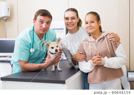 Cheerful mother and daughter visiting veterinarian clinic with their puppy Cheerful mother and daughter visiting veterinarian clinic with their puppy 60648154