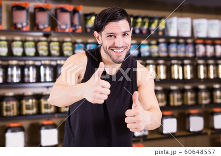 Sportman holding thumbs up in shop of sport nutrition products Sportman holding thumbs up in shop of sport nutrition products 60648557