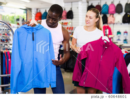 Portrait of happy man and woman holding sportswear in sporting g 60648601