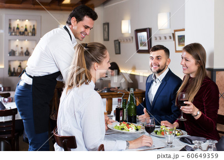 Waiter bringing dishes to guests 60649359
