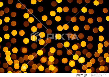 Bright light of orange burning lanterns bokeh from a garland in defocus at night against a dark background Bright light of orange burning lanterns bokeh from a garland in defocus at night against a dark background 60653788