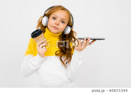 Beautiful teenager caucasian girl listen to music with big earphones and drinks coffee isolated on Beautiful teenager caucasian girl listen to music with big earphones and drinks coffee isolated on 60655394