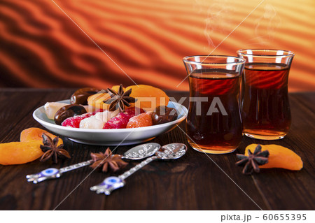 Arabic tea in traditional glasses and oriental sweets on a desert background. Arabic tea in traditional glasses and oriental sweets on a desert background. 60655395