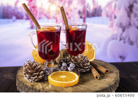 Two glasses of hot mulled wine on the background of a winter landscape. Two glasses of hot mulled wine on the background of a winter landscape. 60655400