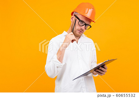Beautiful caucasian engineer man with glasses and orange helmet isolated on yellow background 60655532