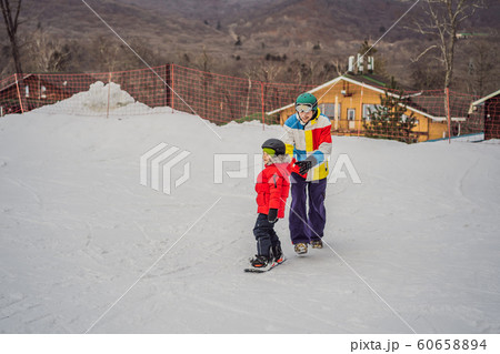 Snowboard instructor teaches a boy to snowboarding. Activities for children in winter. Children's 60658894