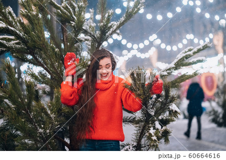 Young woman posing near the Christmas tree on the street 60664616