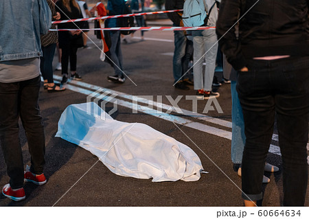Human body covered by a sheet lying on the street. 60664634