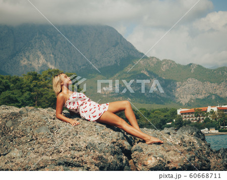 Young woman sitting on the rocks by the sea Young woman sitting on the rocks by the sea 60668711