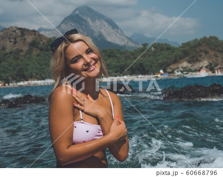 Young woman sitting on the rocks in the sea Young woman sitting on the rocks in the sea 60668796