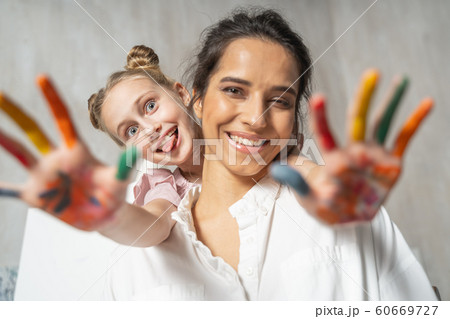 Little pretty daughter with painted palms having fun with her mum 60669727