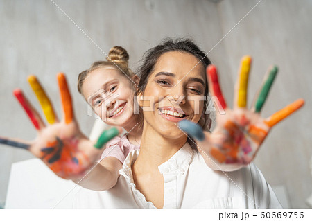 Small pretty daughter with painted palms having fun with her mother 60669756