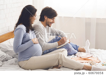 Expecting couple writing checklist before going to maternity hospital 60670058