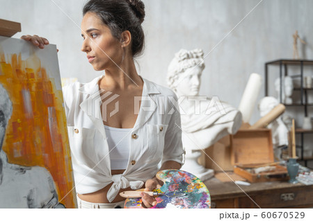 Calm concentrated female artist posing near easel 60670529