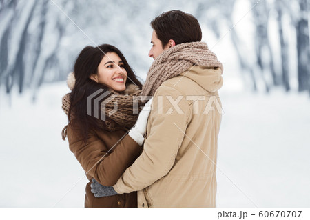 Loving Husband And Wife Hugging Standing In Snowy Park 60670707