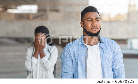 Boyfriend leaving girlfriend after quarrel outdoors, depressed woman crying on background 60670828