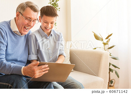 Joyful Grandfather And Boy Using Laptop Laughing Sitting At Home 60671142