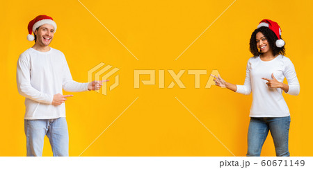 Happy interracial couple pointing fingers at copy space in the middle Happy interracial couple pointing fingers at copy space in the middle 60671149