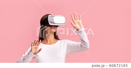 Young Lady In VR Glasses Standing Over Pink Studio Background Young Lady In VR Glasses Standing Over Pink Studio Background 60672193