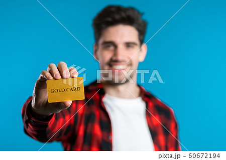 Successful man in plaid shirt showing unlimited gold credit card on blue studio background. Student, money concept Successful man in plaid shirt showing unlimited gold credit card on blue studio background. Student, money concept 60672194