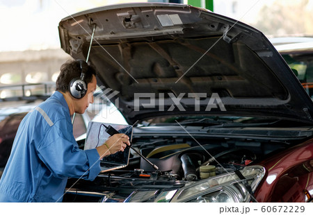 Asian automotive mechanic with blue uniform use electronic tools to check the car Asian automotive mechanic with blue uniform use electronic tools to check the car 60672229