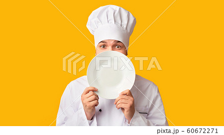 Funny Chef Guy Peeking Out Of Plate Standing In Studio, Panorama Funny Chef Guy Peeking Out Of Plate Standing In Studio, Panorama 60672271