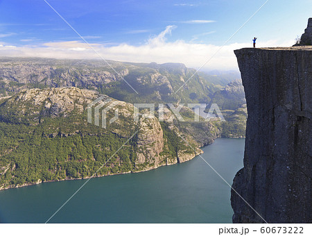 Scenic view of a hiker standing on Preikestolen (Pulpit Rock) and looking on the fjord, Norway Scenic view of a hiker standing on Preikestolen (Pulpit Rock) and looking on the fjord, Norway 60673222