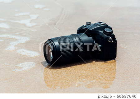 DSLR camera on beach wet from water sea wave 60687640