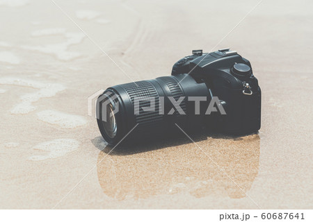 DSLR camera on beach wet from water sea wave DSLR camera on beach wet from water sea wave 60687641