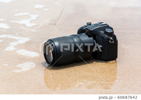 DSLR camera on beach wet from water sea wave DSLR camera on beach wet from water sea wave 60687642