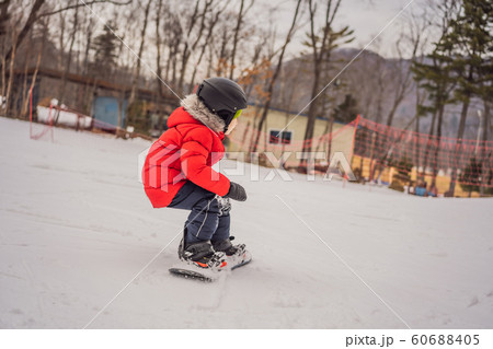 Little cute boy snowboarding. Activities for children in winter. Children's winter sport. Lifestyle Little cute boy snowboarding. Activities for children in winter. Children's winter sport. Lifestyle 60688405
