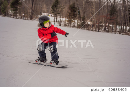 Little cute boy snowboarding. Activities for children in winter. Children's winter sport. Lifestyle Little cute boy snowboarding. Activities for children in winter. Children's winter sport. Lifestyle 60688406