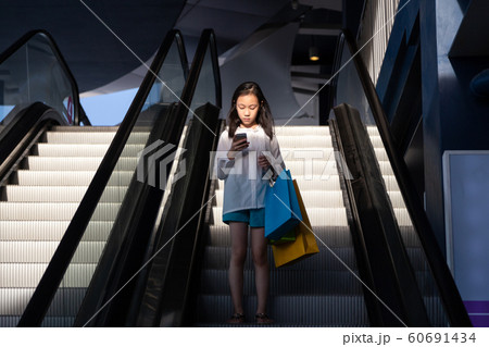 Asian girl on an escalator after a shopping in a store 60691434
