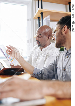 Coworkers discussing financial report Coworkers discussing financial report 60694281