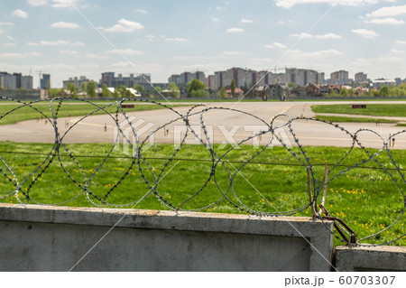 Concrete fence with barbed wire around airport airfield taxiway against blue sky on background. Freedom and security safety concept 60703307