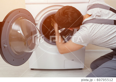 serviceman repairs broken washing machine 60705512