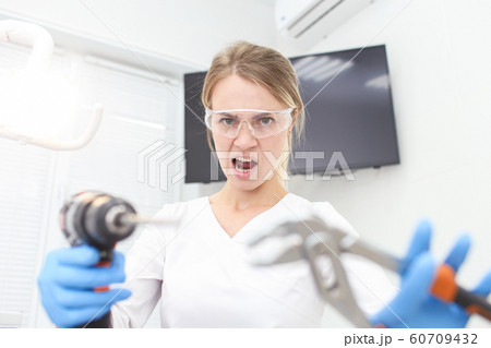 Woman dentist in white uniform holds builder instruments in hands. Selective focus 60709432
