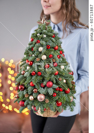 Beautiful small Christmas tree in womans hands. Happy mood. Garland lamp bokeh on background. Wallpaper. Danish pine and fir, Nobilis Beautiful small Christmas tree in womans hands. Happy mood. Garland lamp bokeh on background. Wallpaper. Danish pine and fir, Nobilis 60713887