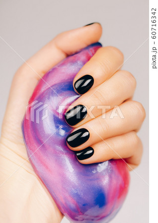 hands with black manicure holding slime 60716342