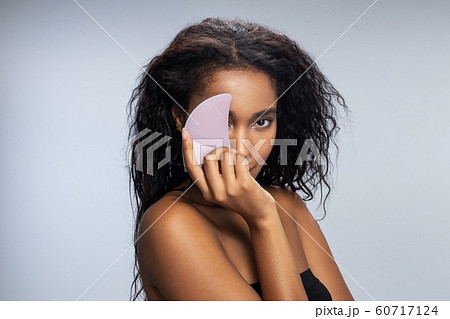 Pretty Afro American lady keeping silicone brush for face in her hand 60717124
