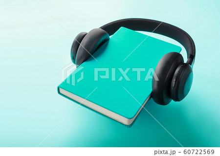 Headphones are worn on a book in a blue hardcover 60722569