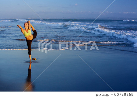 Woman stretching at yoga pose on sunset beach 60729269