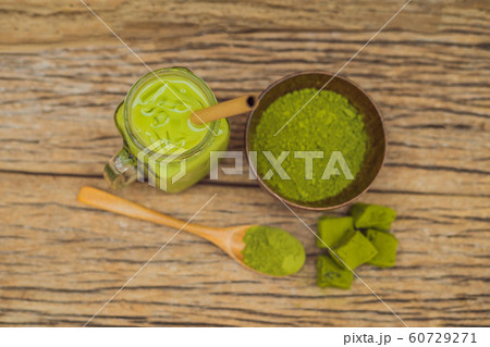 Green tea latte with ice in mason jar, matcha powder and candy made of matcha on wooden background. Homemade Iced Matcha Latte Tea with Milk zero waste Green tea latte with ice in mason jar, matcha powder and candy made of matcha on wooden background. Homemade Iced Matcha Latte Tea with Milk zero waste 60729271