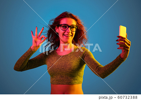 Caucasian woman's portrait isolated on blue studio background in neon light 60732388