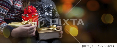 Children's hands are holding a gifts boxes for Christmas or a New Year on the colorful bokhe background. Close Up 60733643