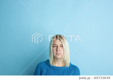 Portrait of young caucasian woman looks happy, dreamful on blue background 60733649