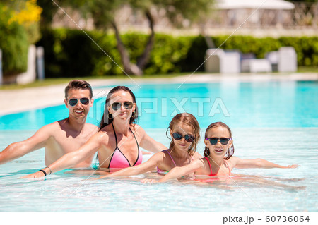 Young family with two kids enjoy summer vacation in outdoor pool 60736064